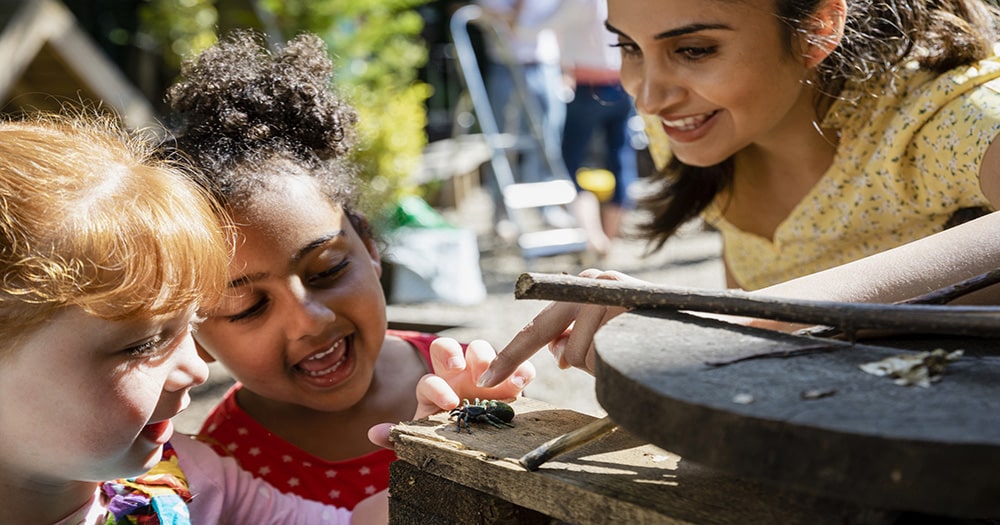 teacher with students looking at bug